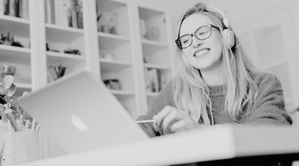 Student sitting at a desk at home working on an Apple MacBook 